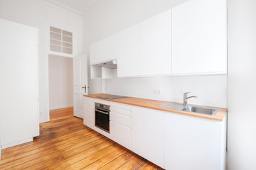 empty, new  built-in kitchen with whote furniture and wooden floor