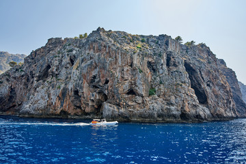 Spain. Mallorca. Motor boat with tourists resting off the rocky shores