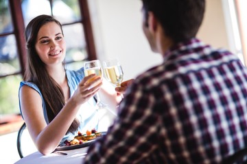 Couple toasting white wine glass in restaurant