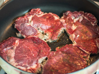 red beef steak being cooked in pan close-up