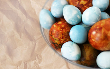 Easter. Marble brown and blue Easter eggs in a transparent vase on the table. Selective focus, macro, toning, blur.