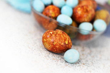 Easter. Marble brown and blue Easter eggs in a transparent vase on the table. Selective focus, macro, toning, blur.