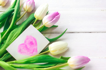 White and purple tulips on a white wooden background. Spring. International Women's Day. Valentine's Day. card with watercolor hearts,Selective focus.