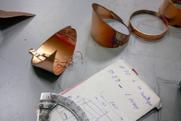 Spun copper pieces of metal on a table close-up. Measuring instrument and product drawing.