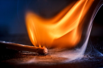 Macro shooting of a burning match with a flame of fire and smoke on a black background