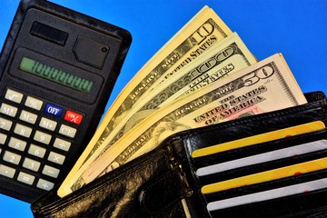 wallet with money of different banknotes, calculator for settlements and Bank cards, on a blue...