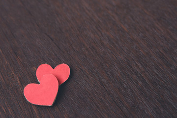 Obraz premium Valentines Day background with red heart shape on dark wooden background with copy space