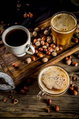 Homemade hazelnut coffee latte or cappuccino, rustic wooden background with hazelnuts, three coffee cups copy space