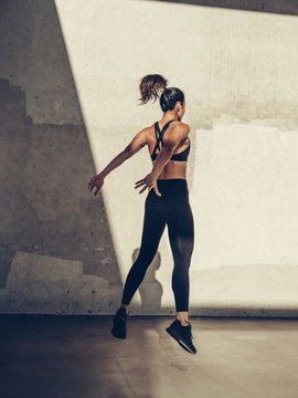 Rear view of female athlete exercising near wall