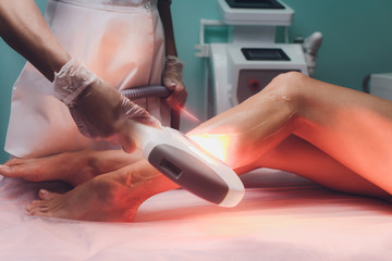 beautician removes hair on beautiful female legs using a laser. hair removal on the legs, laser...