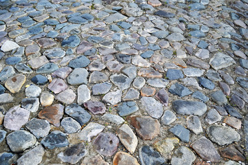 Cobblestone pavement textured pattern of narrow retro street. A fragment of the old town square with a road surface, a typical European urban road material.