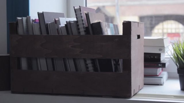 Slider shot of box with books on window, rollover shot