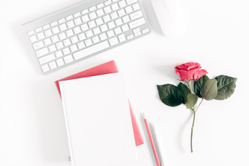 Female desktop, сomputer keyboard, notebook, bouquet roses on white background. Flat lay, top view, copy space