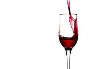 red wine pouring into wine glass isolated. Splash of red wine in a glass on a white background with reflection