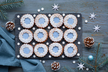 Top view of flower Linzer cookies with blue glazing on dark winter background