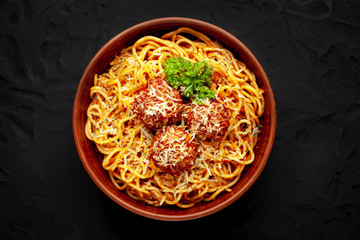 Italian pasta with tomato sauce and meatballs in a plate, dark background
