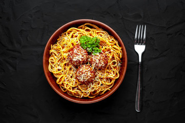 Italian pasta with tomato sauce and meatballs in a plate, dark background