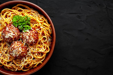 Italian pasta with tomato sauce and meatballs in a plate, dark background