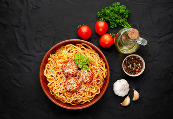 Italian pasta with tomato sauce and meatballs in a plate, dark background