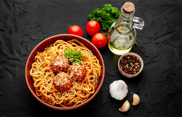 Italian pasta with tomato sauce and meatballs in a plate, dark background