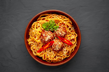 Italian pasta with tomato sauce and meatballs in a white plate, gray background