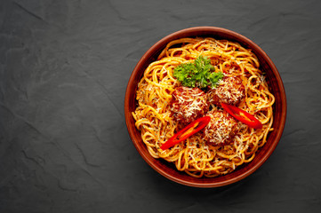 Italian pasta with tomato sauce and meatballs in a white plate, gray background