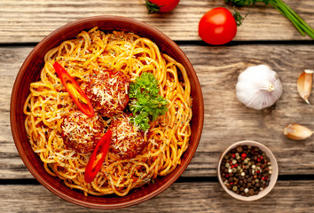 Italian pasta with tomato sauce and meatballs in a plate on a wooden table