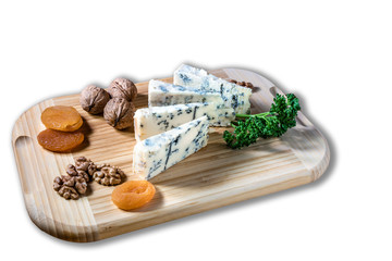 Some peaces of the cheese blue mold roquefort  with dried apricot and peaces of the nuts with parsley at the wooden desk and background