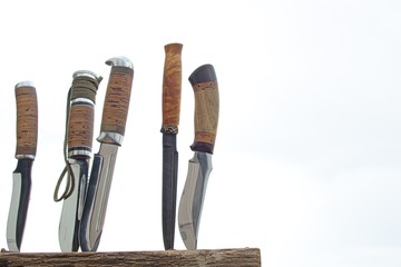 hunting knives stuck in an old snag on a cloudy background