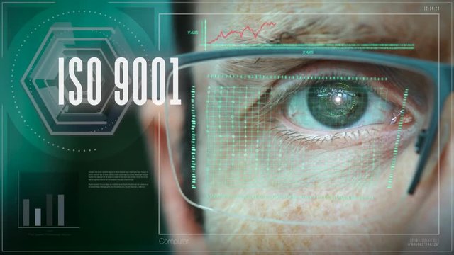 A close up of a businessman eye controlling a futuristic computer system with a Business ISO 9001 concept.