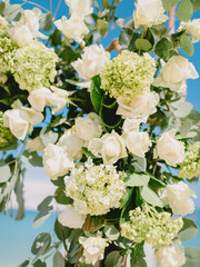 Floral decoration for wedding arch with white flowers and leaves.