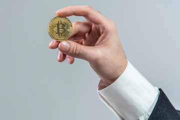 Businessman's fingers holding a bitcoin golden penny, white background