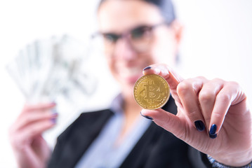Smiling business woman holding a pile of money and a golden bitcoing indicating her success in bitcoin trading and mining
