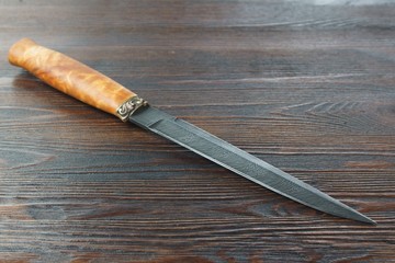 hunting knife from Damascus steel on wooden background