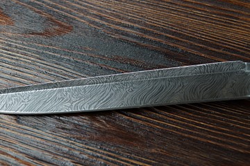 hunting knife from Damascus steel on wooden background