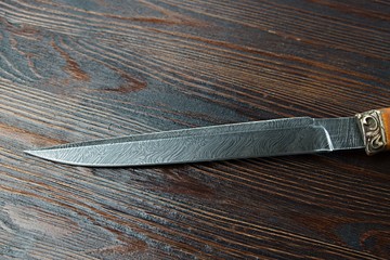 hunting knife from Damascus steel on wooden background
