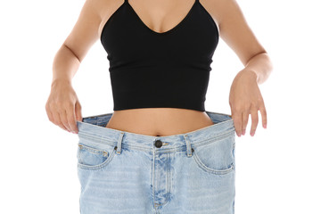 Slim woman in oversized jeans on white background, closeup. Weight loss