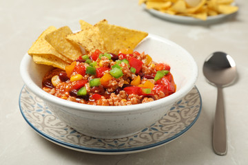 Chili con carne served with tortilla chips in bowl on table