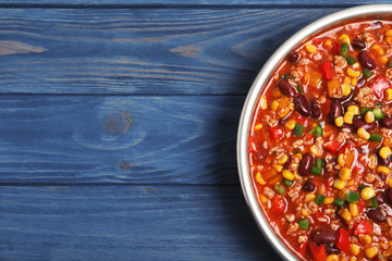 Frying pan with chili con carne on wooden background, top view. Space for text