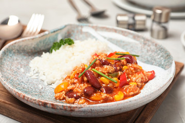 Plate of tasty chili con carne with rice on gray table