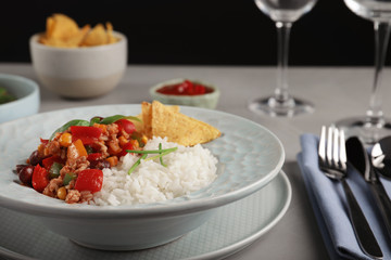 Tasty chili con carne served with rice on gray table. Dinner in restaurant