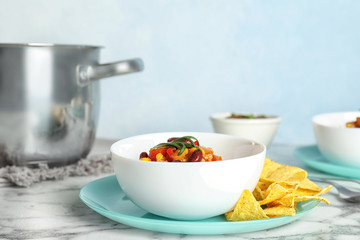 Bowl with tasty chili con carne served on marble table