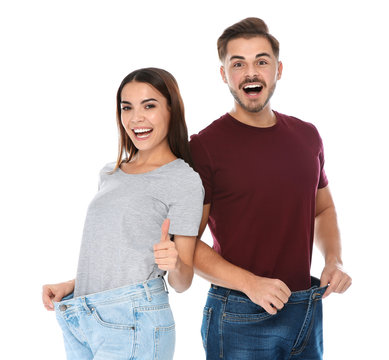Fit people in oversized jeans on white background. Weight loss
