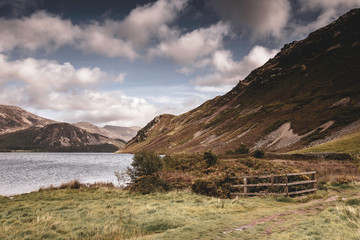 Scenic landscape of Lake District,Cumbria,Uk.Mountain, lake and view on scenic valley.Wooden fence on lake shore and natural light on hill slope.