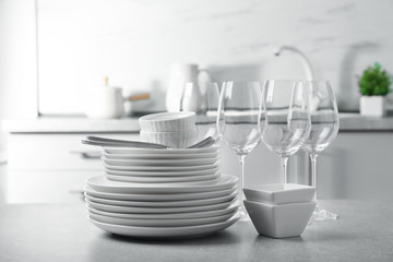 Set of clean dishes and cutlery on table in kitchen