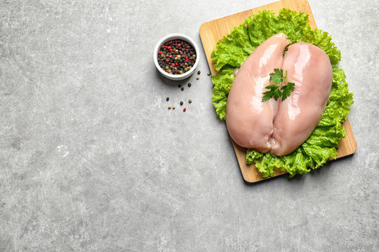 Flat lay composition with raw chicken breasts and space for text on grey background