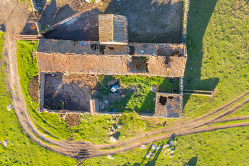 An aerial view directly above of the amazing "Dehesa Extremeña" with an old shed in ruins with some tiles from the roof broken. Storage in the past at the Spanish countryside in Extremadura region

