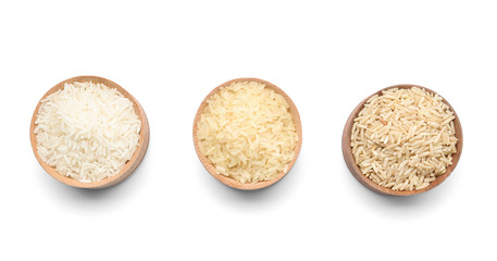 Bowls with different types of uncooked rice on white background, top view