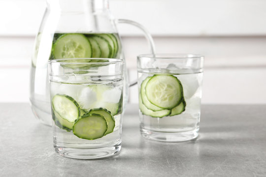 Glasses and jug of fresh cucumber water on table
