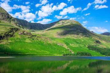 Idyllic scenery of rural Cumbria,UK on beautiful spring day.Green hill, mountain lake and blue sky with few clouds.Landscape photography.